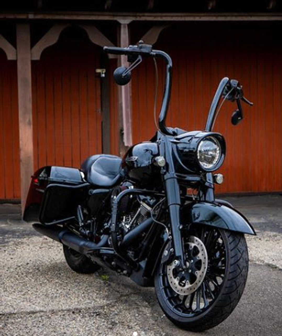 A black Factory 47 motorcycle parked in front of a barn.