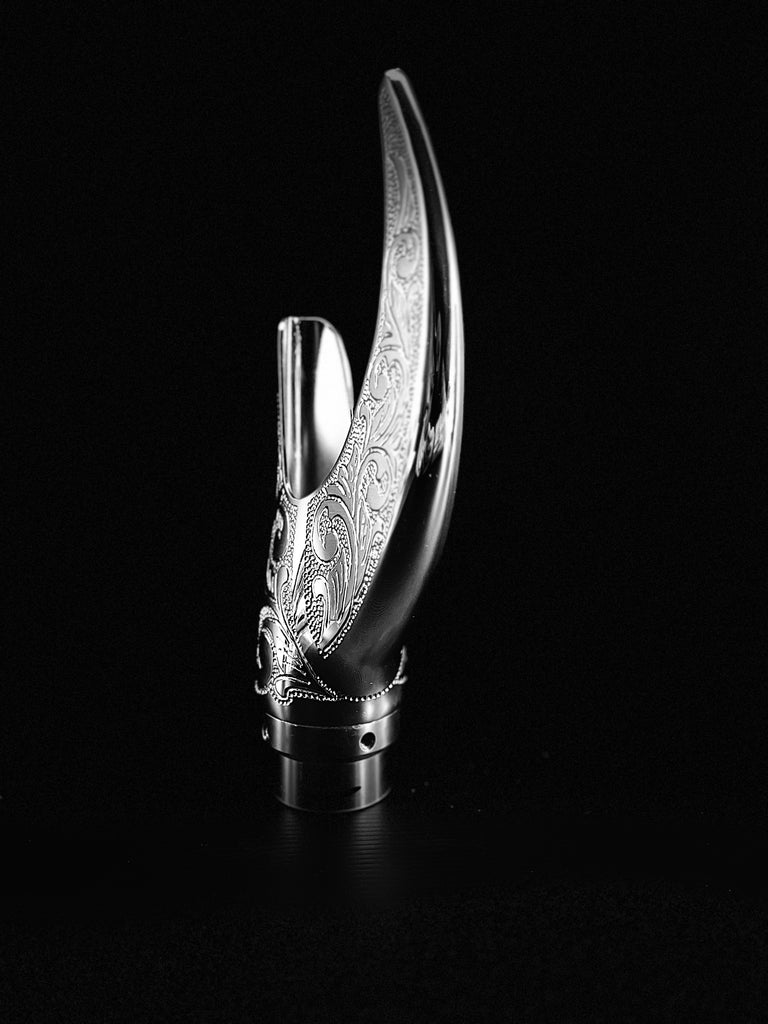 A silver Reaper Exhaust Tips with an ornate design on it from the brand Cuztom Kraft.