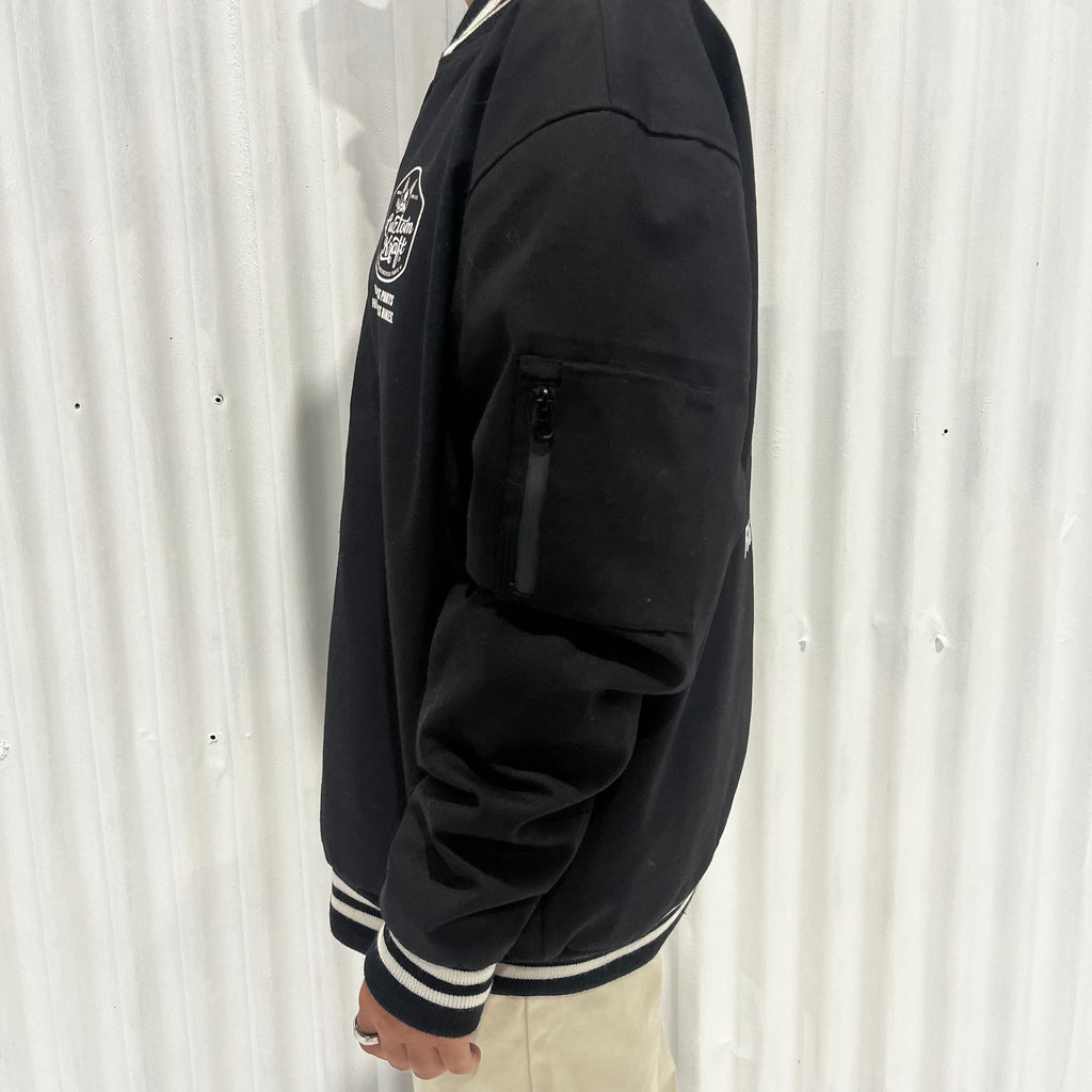 A man wearing a 'Bad Ass' jacket made by Cuztom Kraft and khaki pants.