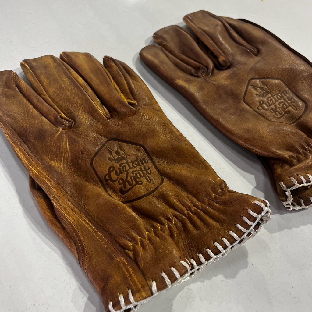 Two Bad Ass Leather Riding Gloves - Tan by Cuztom Kraft on a table.