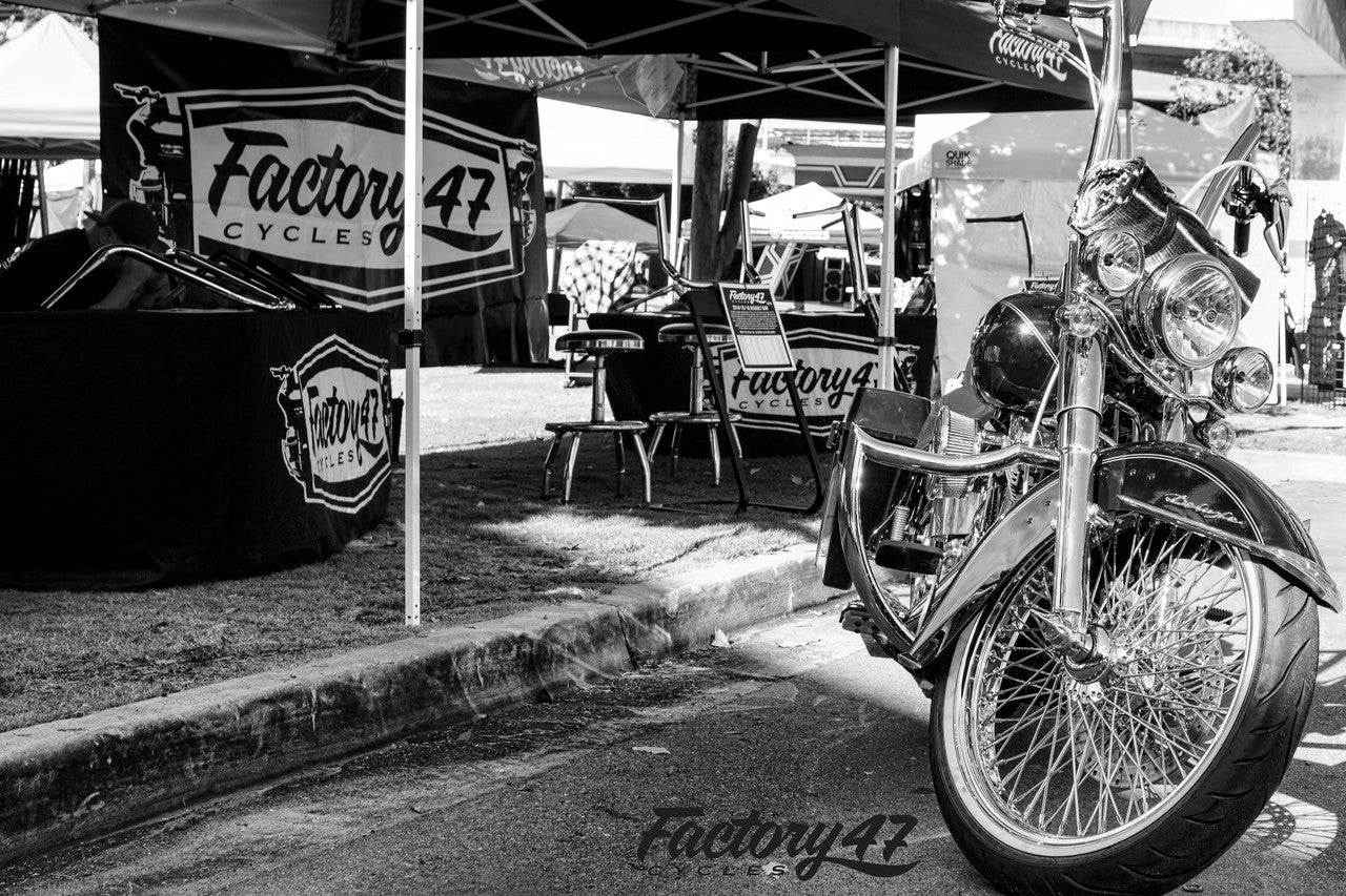 A black and white photo of a Factory 47 Shield 2001-2017 Softail motorcycle parked under a tent.