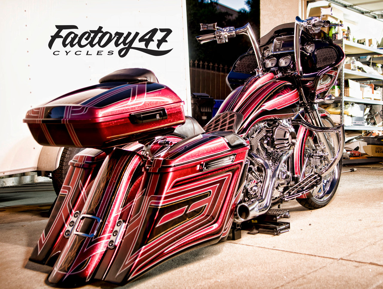 A red and black Factory 47 Signature Handlebar Chrome 14" motorcycle parked in front of a building.