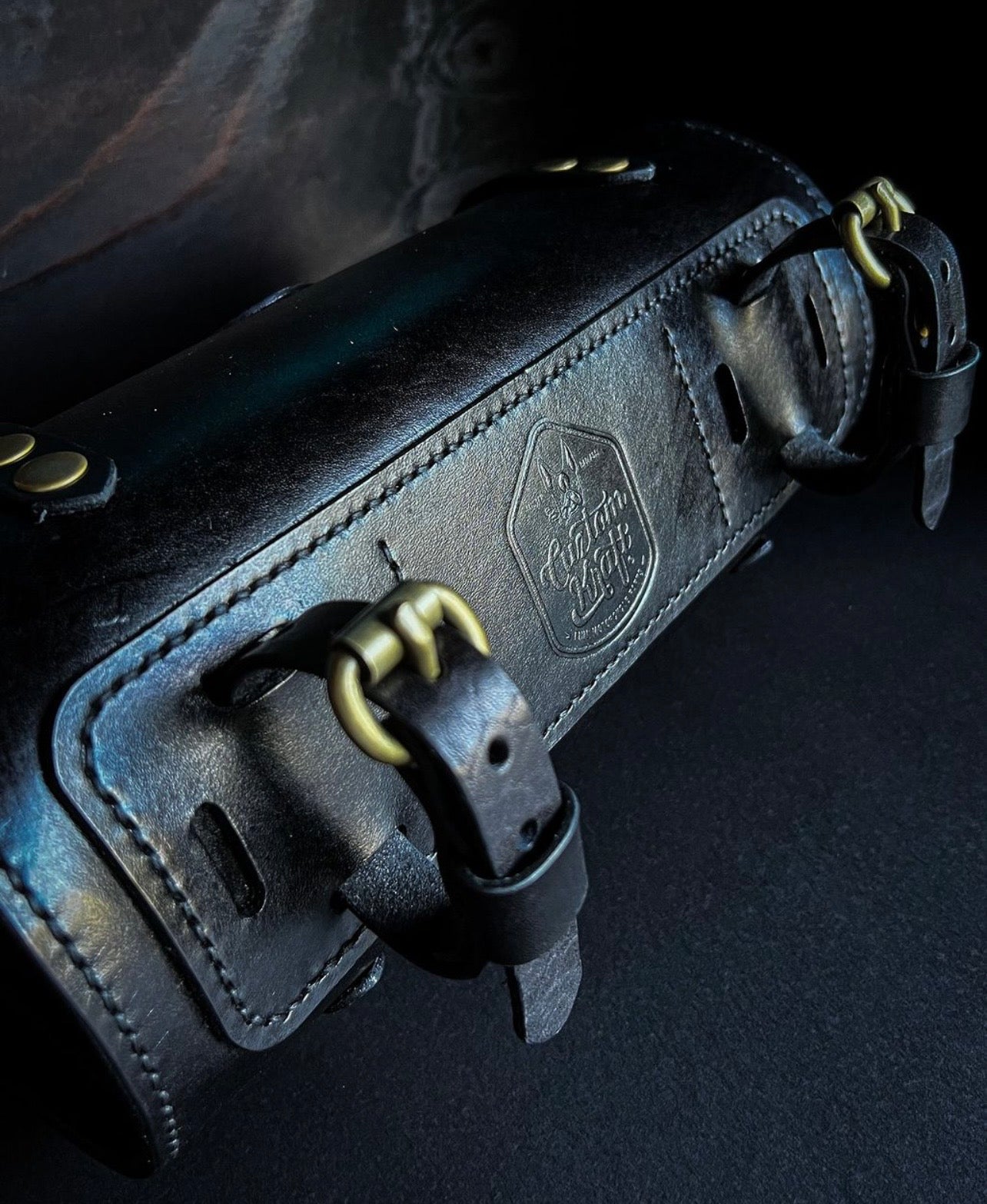 A Cuztom Kraft Leather Roll Bag with brass hardware.