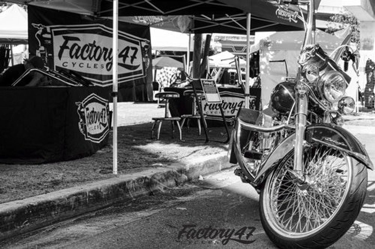 A black and white photo of a Factory 47 Shield 2001-2017 Softail motorcycle parked in front of a tent.